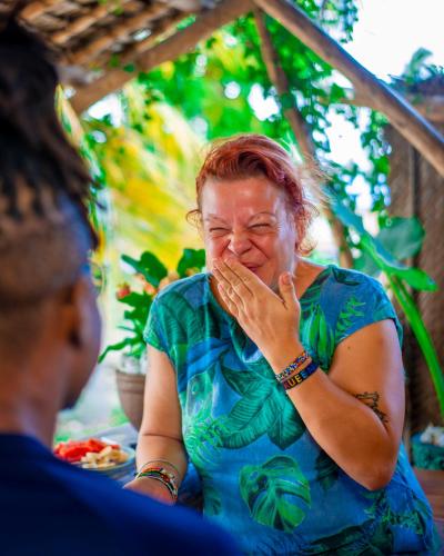 a woman sitting at a table with her hand to her mouth at PALM - 2minutes walk to the beach in Nungwi