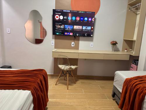 a room with two beds and a desk with a tv at Apto com Varanda Próximo da Orla in Marabá