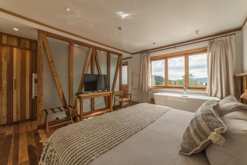 a bedroom with a bed and a tub and a television at Hotel Termas Puyehue Wellness & Spa Resort in Puyehue