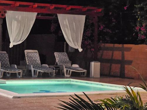a swimming pool with chairs and a gazebo at Royal Escape - 2 in Anse La Raye