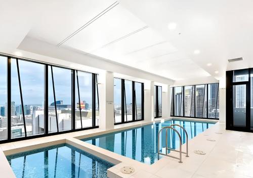 a swimming pool in a building with windows at Melbourne's Premium on Collins in Melbourne