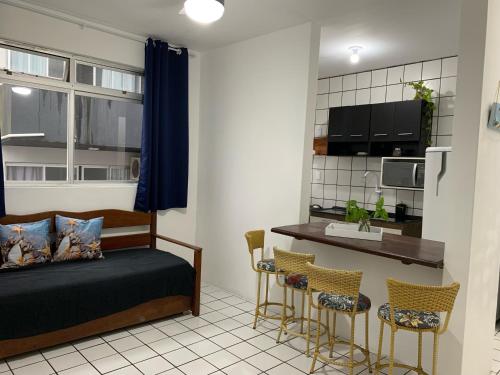 a bedroom with a bed and two chairs and a kitchen at Sol-datelli Apês Floripa in Florianópolis