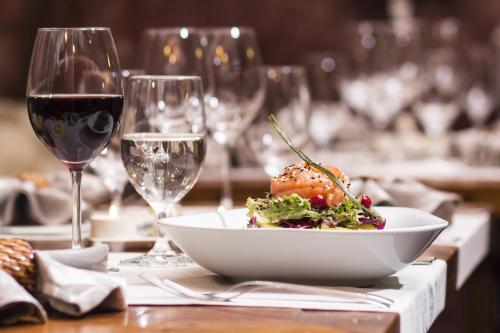 uma mesa com uma tigela de comida e copos de vinho em Adonis Le Chastellan em Valberg