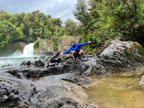 a man sitting on a rock in front of a waterfall at Hotel Termas Puyehue Wellness & Spa Resort in Puyehue