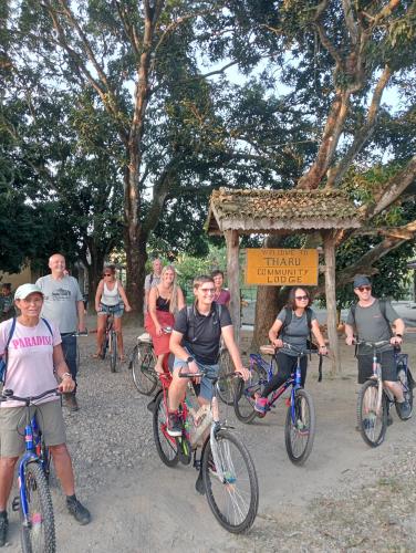 a group of people riding bikes in front of a sign at Tharu Community Lodge in Kawasoti