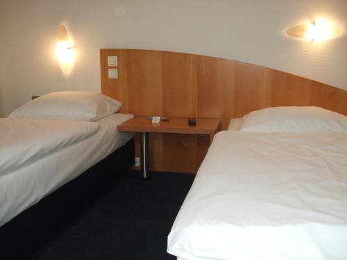 a hotel room with two beds and a table at Sporthotel Wiedenbrueck in Rheda-Wiedenbrück