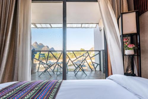 a bedroom with a bed and a balcony with a view at Secret Courtyard Resort Hotel in Guilin