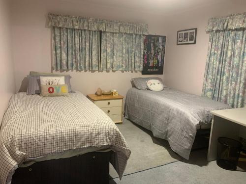 a bedroom with two beds and a desk and curtains at RUs Terraces in Kauri