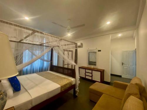 una camera con letto, divano e specchio di Villa 59- Luxurious Beach house in Ambalangoda a Ambalangoda