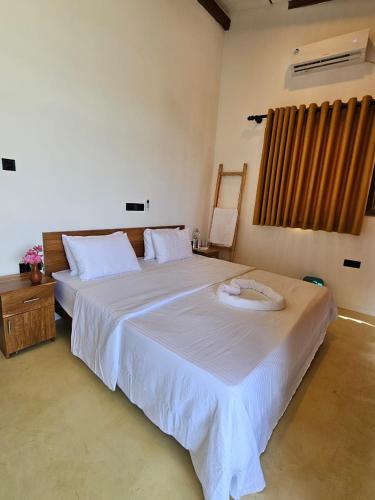 a bedroom with a large white bed and a window at Muthu Sea View Hiriketiya in Hiriketiya