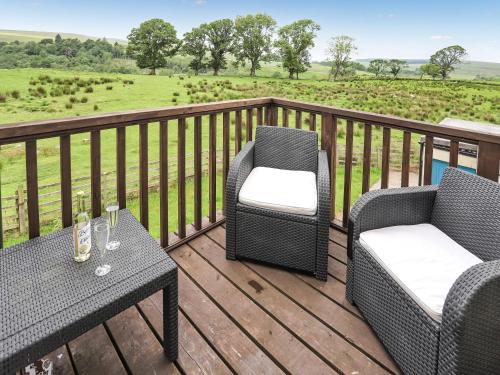 two chairs and a table on a deck with a field at Stargazers - Uk3445 in Greenhaugh