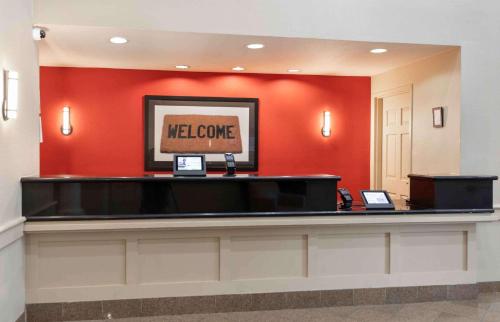 a welcome desk in a hotel lobby with a red wall at Extended Stay America Suites - Dallas - Plano in Plano