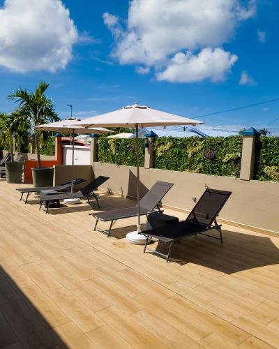 a group of chairs and umbrellas on a patio at Evasion en plein cœur de la ville Studio Jacuzzis Sauna et piscine au centre de Port-Louis in Port-Louis