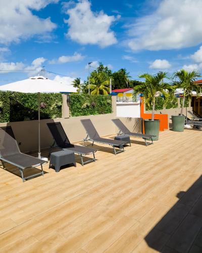 a group of chairs and an umbrella on a wooden deck at Evasion en plein cœur de la ville Studio Jacuzzis Sauna et piscine au centre de Port-Louis in Port-Louis