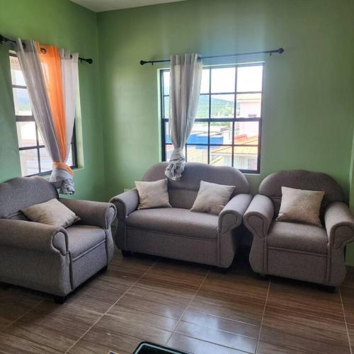 a living room with two couches and two windows at vieux fort town apartment in Vieux Fort