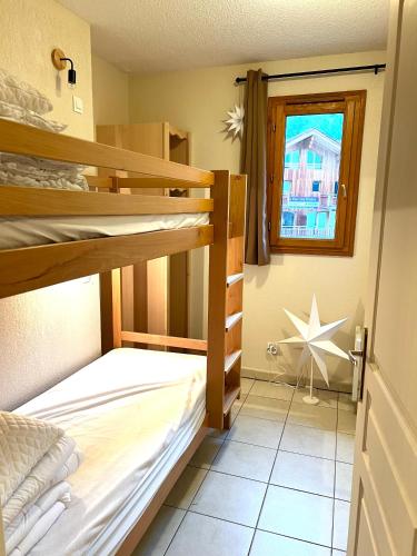 une chambre avec deux lits superposés et une fenêtre dans l'établissement Le Lodge d’Orres Appartement 6p les Orres 1800, aux Orres