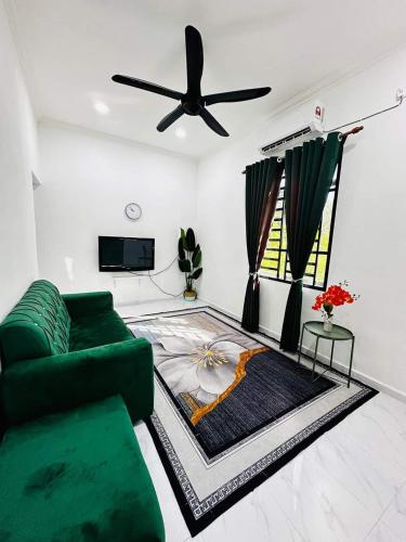 a living room with a green couch and a ceiling fan at Homestay Nurwan in Bukit Mertajam
