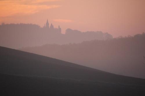 a foggy field with a castle in the background at sunset at La Grande Oasis - B&B et Spa in Grazac