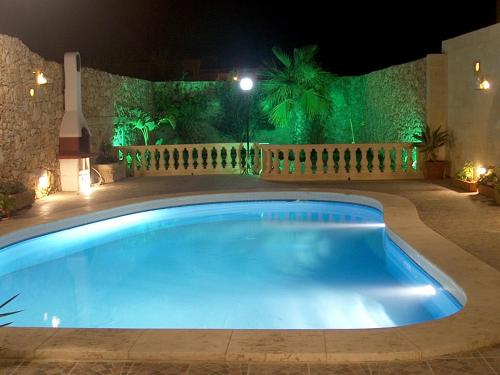 a large swimming pool in a yard at night at Barumbara Farmhouse in Sannat