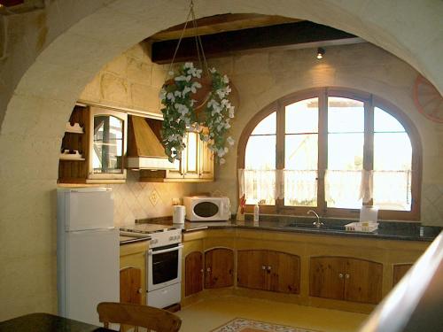 a kitchen with an arched window and a white refrigerator at Barumbara Farmhouse in Sannat