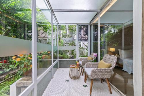 a glass conservatory with two chairs and a table at 6號花園別墅酒店 Shenzhen No'6 Garden Villa --French Window with garden view,Close to Sea World &Shekou Ferry Port &K11 Ecoast &Subway Nearby ,Offer Western food and coffee &English speaking with tour services in Shenzhen