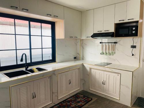 a kitchen with white cabinets and a sink and a window at Huang Su Villa 2 皇宿2号泳池别墅 in Nong Prue