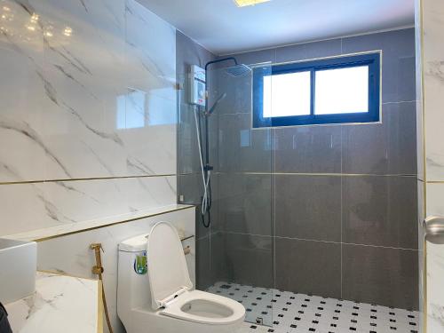 a bathroom with a toilet and a shower with a window at Huang Su Villa 2 皇宿2号泳池别墅 in Nong Prue