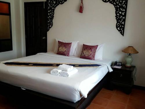 a bedroom with a bed with two towels on it at Wangburapa Grand Hotel in Chiang Mai
