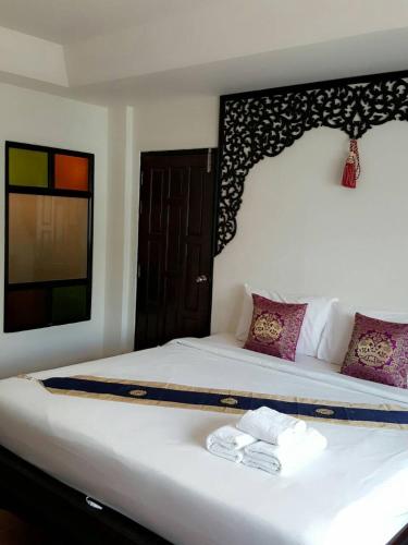 a bedroom with a large white bed with towels on it at Wangburapa Grand Hotel in Chiang Mai