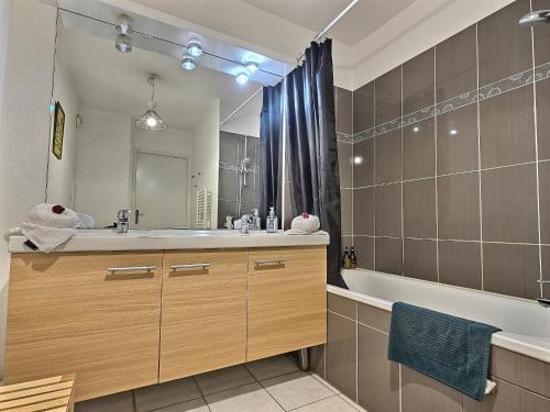 une salle de bain avec un lavabo, une baignoire et un miroir dans l'établissement Le cocon d'Ariane *Disney*Paris*Gare à 100m*, à Chessy