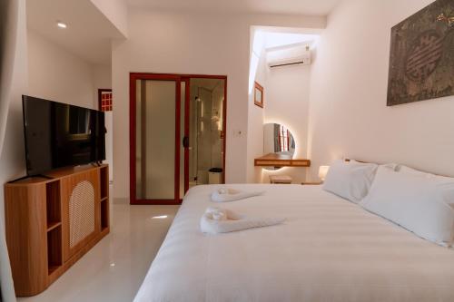 a bedroom with a white bed and a television at Hue River Side Villa in Hue