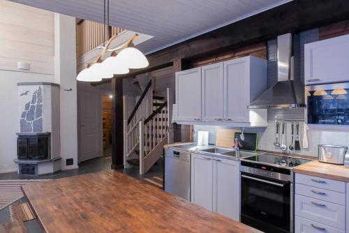 a kitchen with white cabinets and a wooden counter top at Koskikara in Äkäslompolo