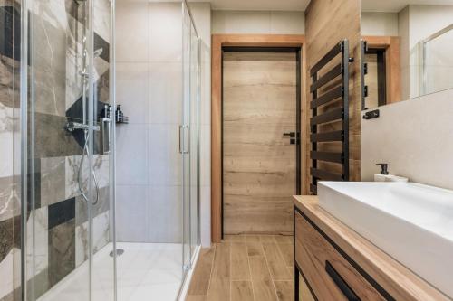 a bathroom with a glass shower and a sink at Apres Ski Bachleda - LoftAffair Collection in Zakopane