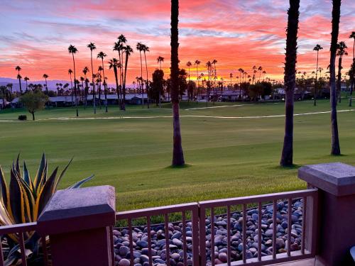 a sunset over a golf course with palm trees at The Country Club Experience in Palm Desert