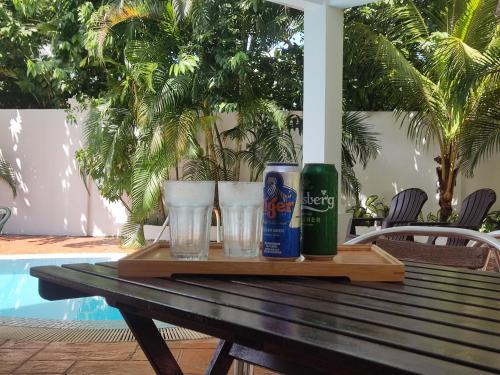 a wooden table with two glasses and two cans of beer at Rumah Putih B&B near KLIA in Sepang