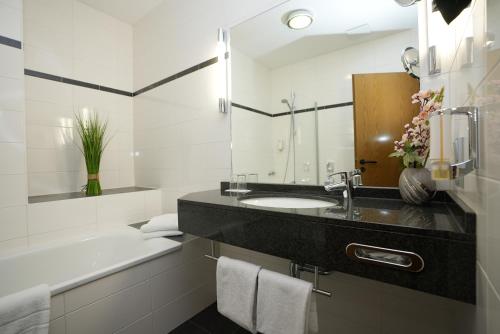 a bathroom with a sink and a bath tub at UNO Hotel Posthof Saarlouis in Saarlouis