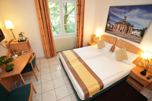 a hotel room with a large bed and a desk at UNO Hotel Posthof Saarlouis in Saarlouis