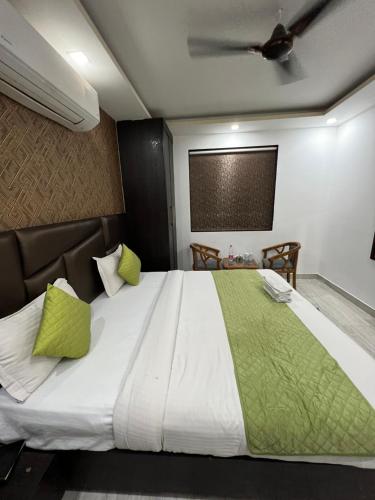 a bedroom with a large white bed with green pillows at Hotel Royal Inn igi in New Delhi