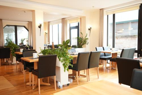 a dining room with tables and chairs and windows at UNO Hotel Posthof Saarlouis in Saarlouis