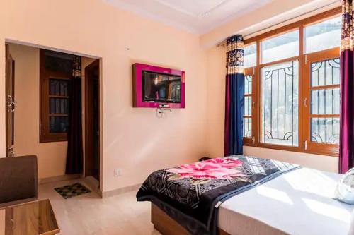 a bedroom with a bed and a tv on the wall at Indu BNB Shimla in Shimla