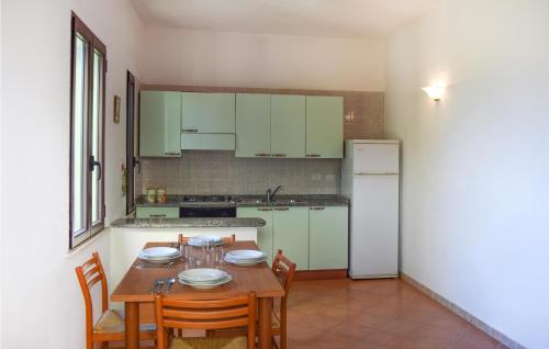 a kitchen with a wooden table with chairs and a refrigerator at Vespucci in Costa Rei