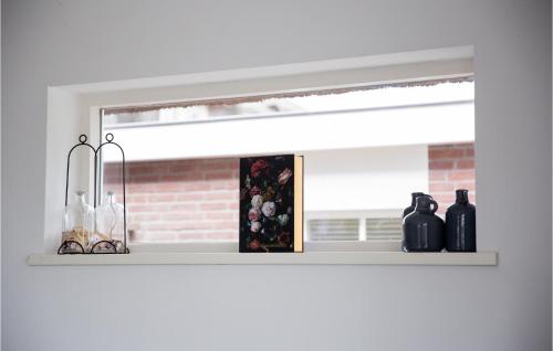 a shelf with bottles and vases on it in front of a window at Holiday Home Breukelen Iv in Breukelen
