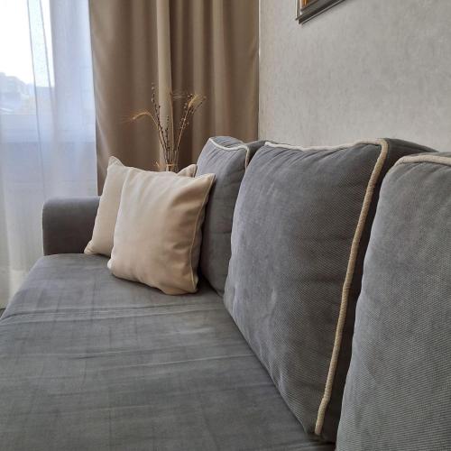 a gray couch with pillows in a living room at The Central Collection Apartments in Chişinău