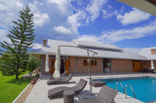 a house with a swimming pool with chairs and an umbrella at The Wes Village, incl free Breakfast & free today's dish Thai food dinner in Chiang Dao