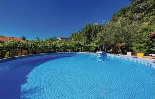 a large blue swimming pool with trees in the background at 1 Bedroom Pet Friendly Home In Lovran in Lovran