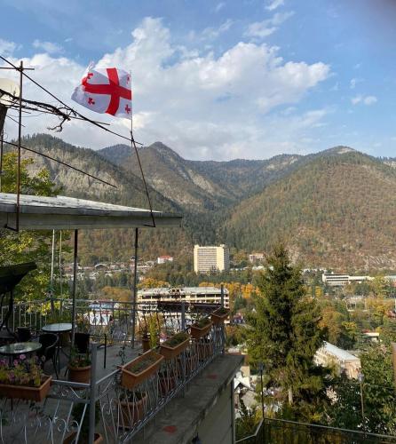 a flag flying on top of a building with mountains in the background at Anano's House in Borjomi