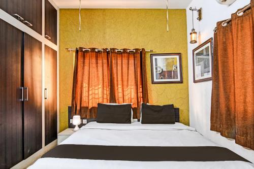 a bedroom with a large bed with an orange curtain at Hotel O Home Bm-x in Khandagiri