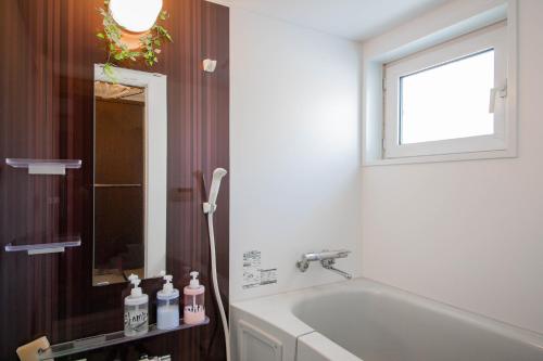 a bathroom with a tub and a window and a sink at DOWNTOWN　TOKO11 in Asahikawa