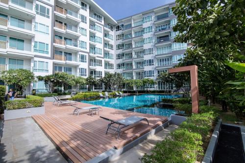 un edificio de apartamentos con terraza de madera y piscina en First Choice Grand Suites Sha Plus Extra en Hua Hin