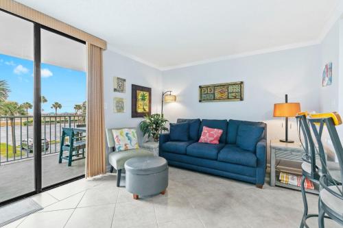 a living room with a blue couch and a balcony at Gulf Shores Surf & Racquet Club 212A in Gulf Shores